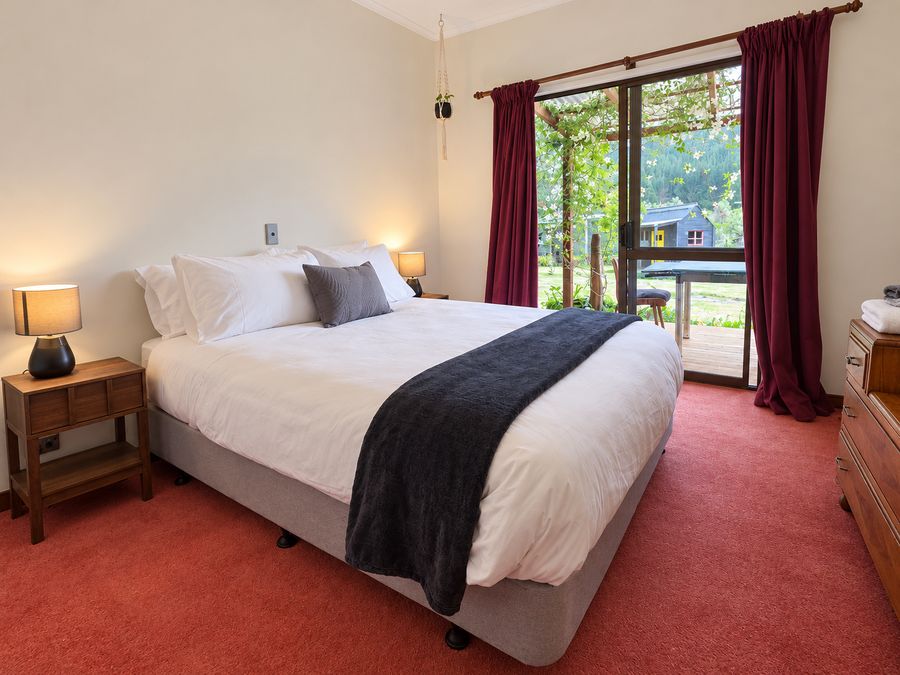 Bedroom with red curtains and a sliding door out to the garden
