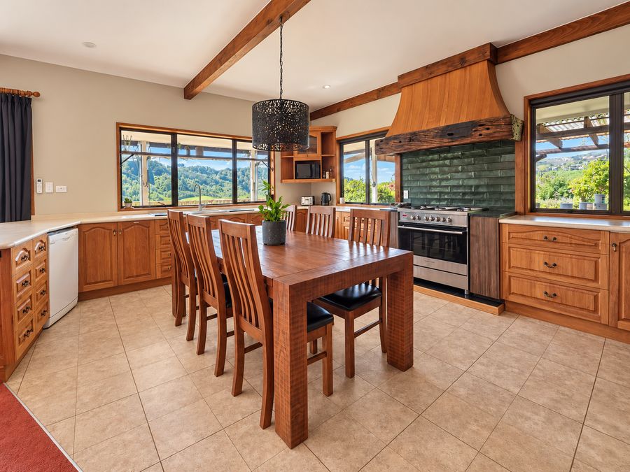 Kitchen with timber cabinets, gas range and dining table