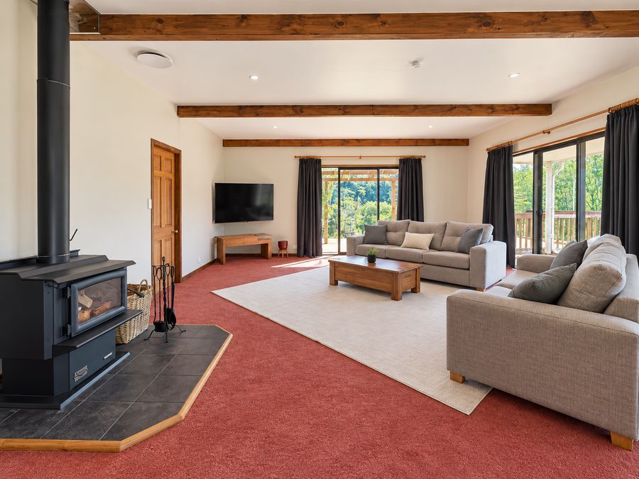 Lounge with wood burner, exposed beams and sliding doors to the deck