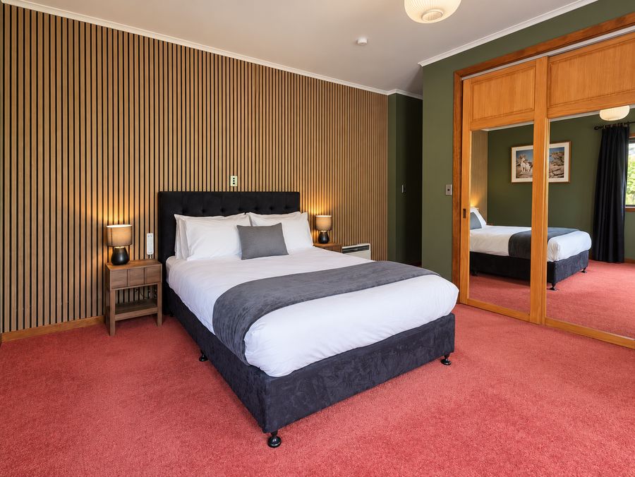 Master bedroom with green walls, slatted timber feature wall and mirrored wardrobe