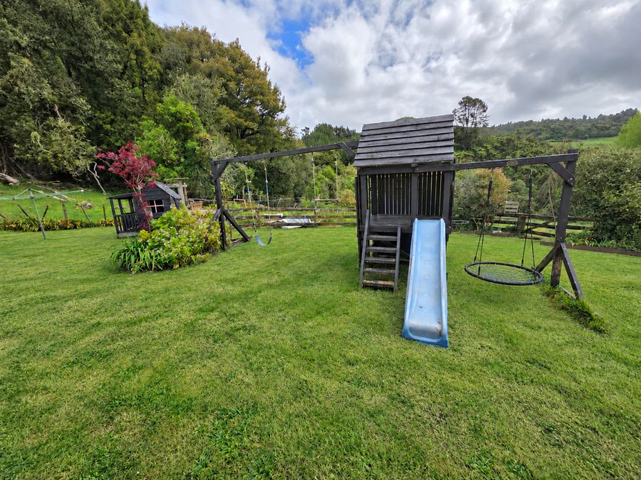Wooden play fort with swings and a blue slide on the lawn